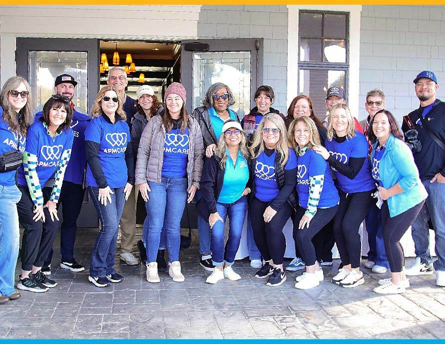 APM Cares volunteers standing together in a group at a community function APM Cares volunteers standing together in a group at a community function